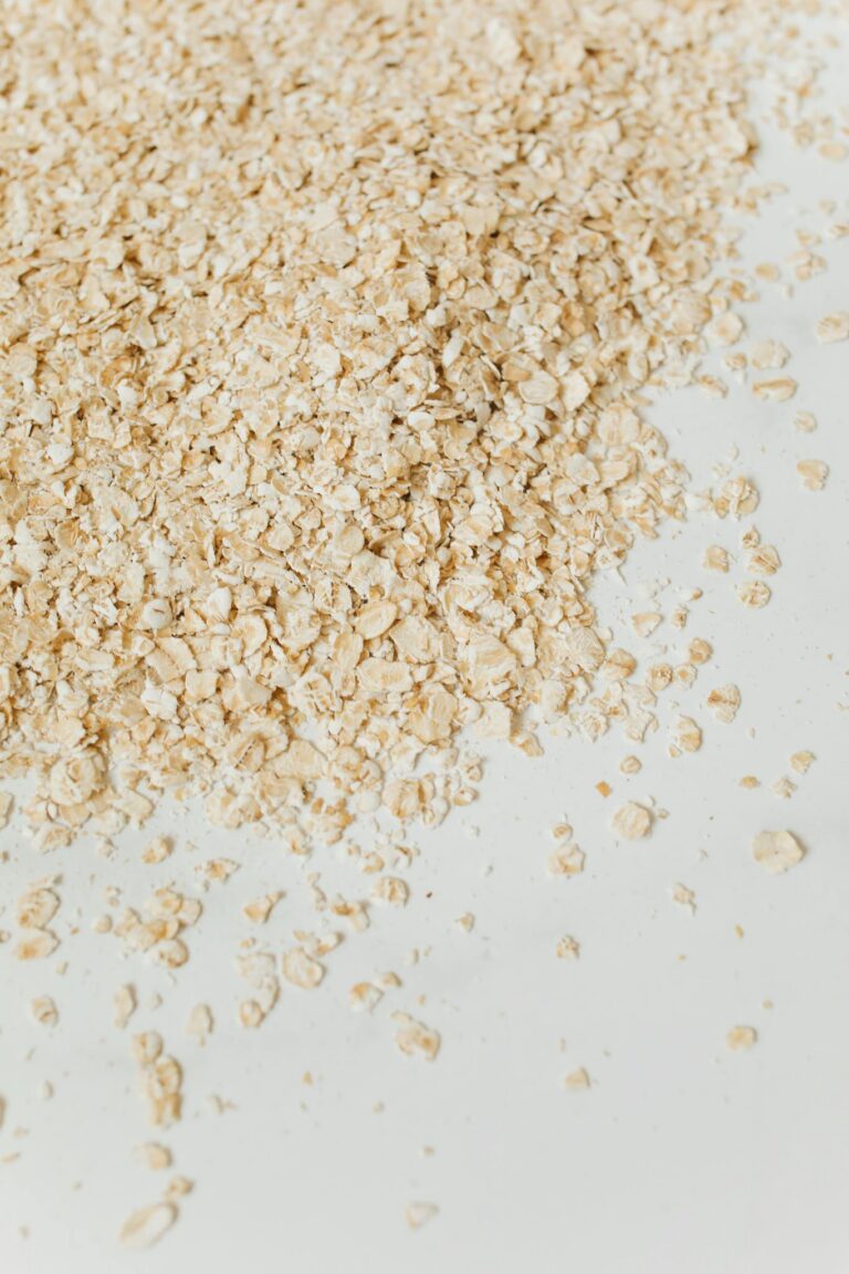 Close-up of raw oats scattered on a white surface, highlighting texture.