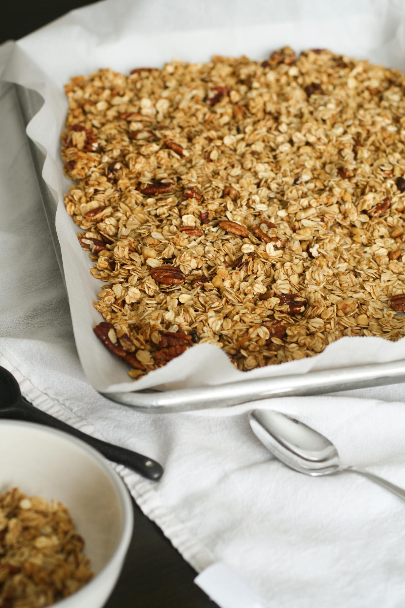 Freshly baked homemade granola with oats and nuts on a baking tray.